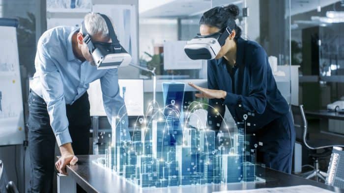 Male and Female Architects Wearing Augmented Reality Headsets Work with 3D City Model. High Tech Office Professional People Use Virtual Reality Modeling Software Application.