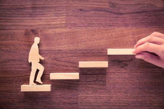 Wooden Figurine Of A Man Climbing Up Stairs