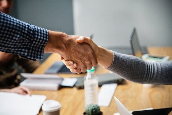 Two People Shaking Hands During A Business Meeting