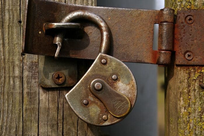 An open padlock on a gate.