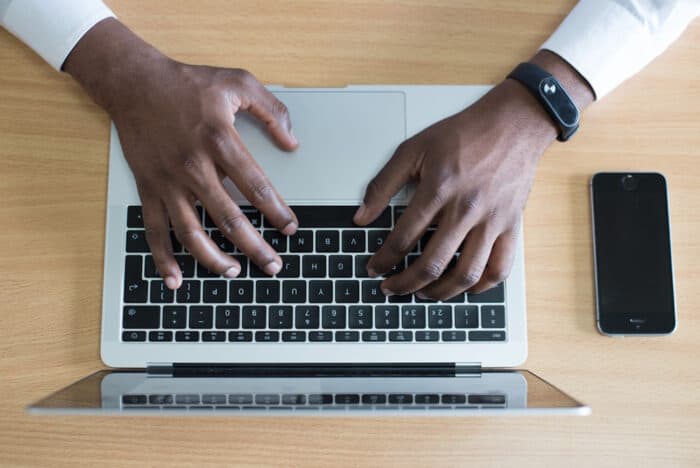 Overhead view of hands typing on a laptop